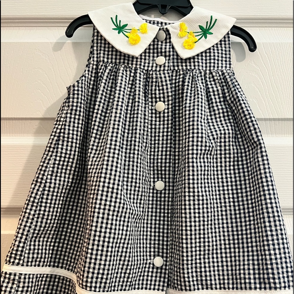 Black and white checkered dress with yellow flowers on collar.